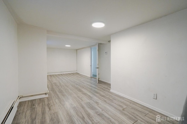 spare room with baseboards, a baseboard heating unit, and wood finished floors