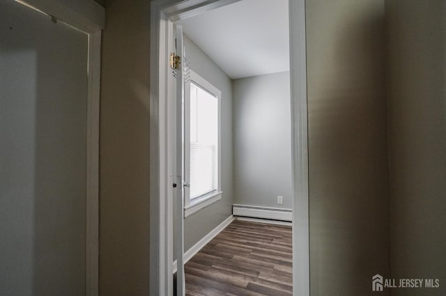 corridor with dark wood-type flooring, a baseboard radiator, and baseboards