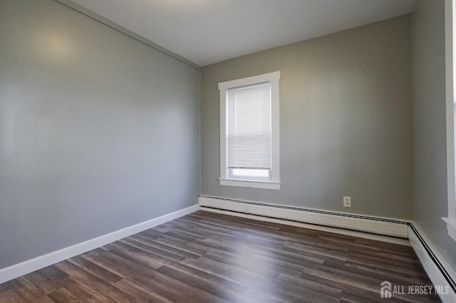 spare room with a baseboard radiator, dark wood finished floors, and baseboards