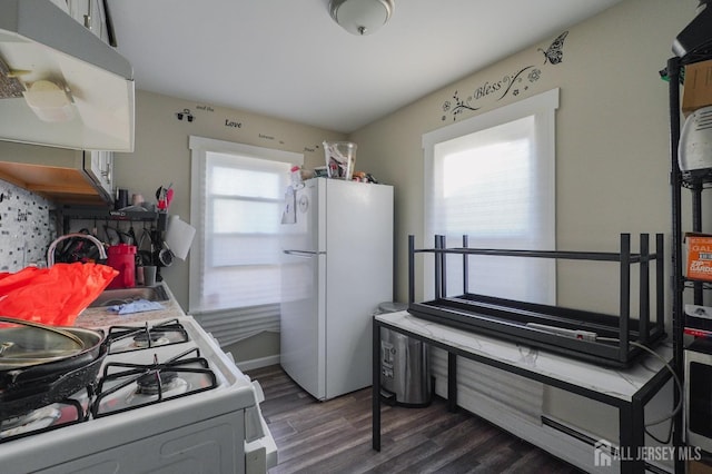 kitchen featuring white appliances, dark wood-type flooring, and a sink