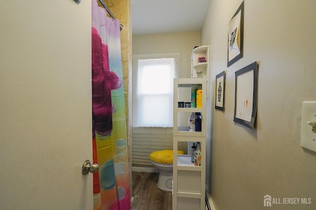 full bathroom featuring a shower with shower curtain, toilet, and wood finished floors