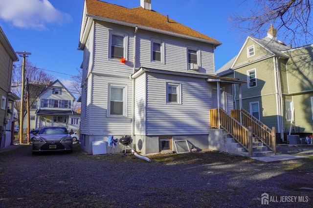 back of property featuring a chimney, a residential view, and central air condition unit