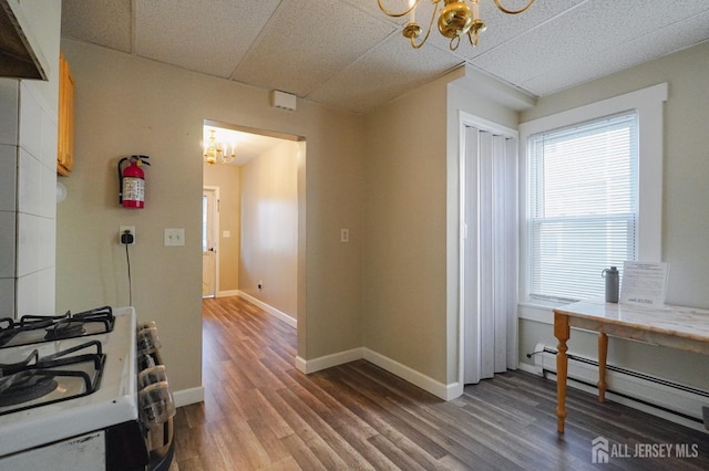 kitchen with a baseboard radiator, white range with gas cooktop, a chandelier, and a paneled ceiling