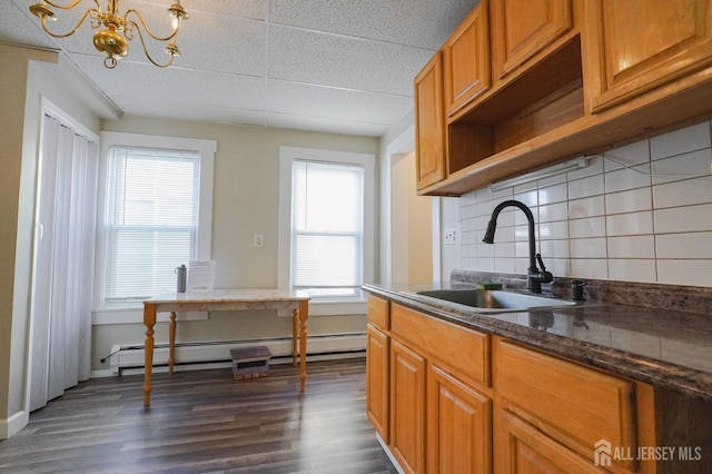 kitchen featuring dark wood-type flooring, backsplash, a sink, and a wealth of natural light