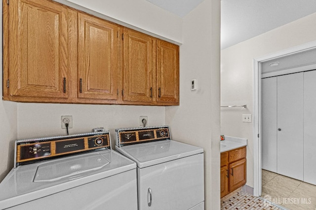 washroom featuring cabinets, light tile patterned flooring, and washing machine and clothes dryer