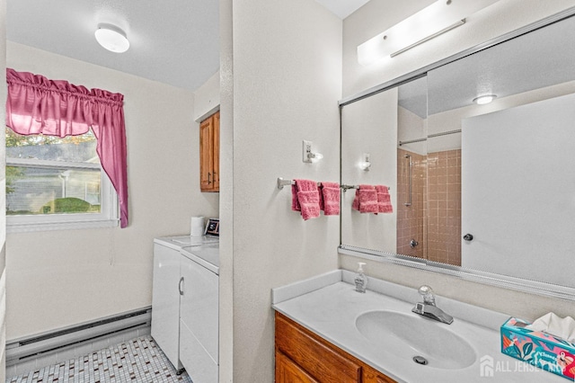 bathroom with baseboard heating, vanity, washer and clothes dryer, and walk in shower