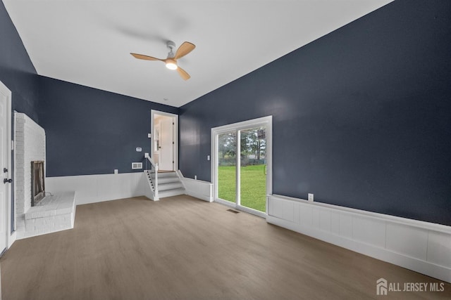 344 W Point Ave W, Franklin Twsp, NJ 08873 - unfurnished living room with visible vents, wainscoting, a brick fireplace, wood finished floors, and a ceiling fan