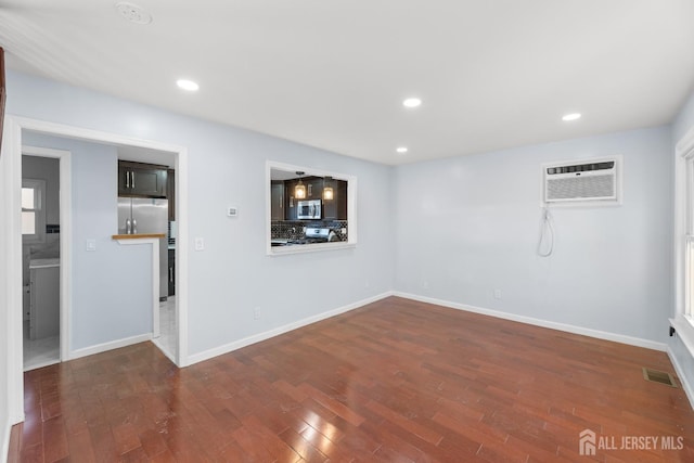 unfurnished room featuring an AC wall unit, recessed lighting, and wood finished floors