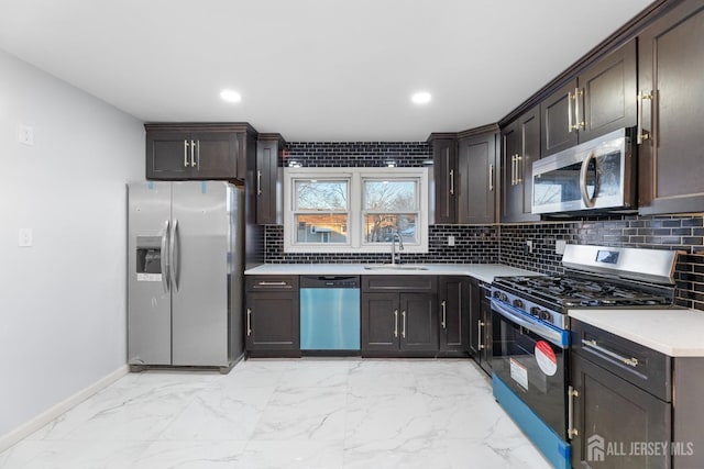 kitchen with backsplash, light countertops, marble finish floor, stainless steel appliances, and a sink