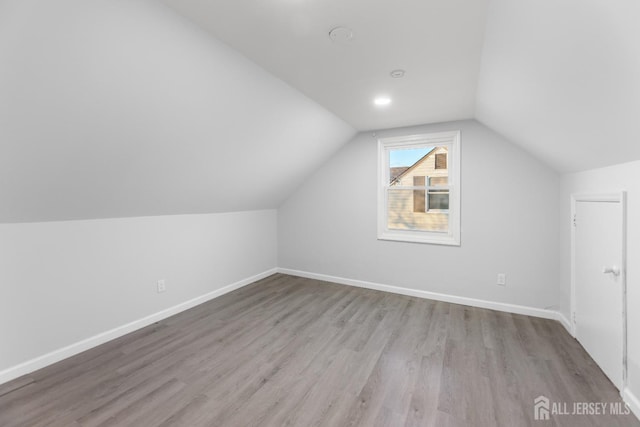 additional living space featuring vaulted ceiling, baseboards, and wood finished floors