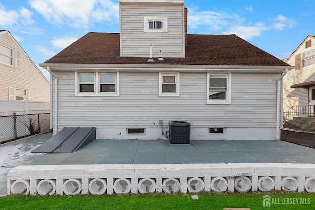 rear view of property featuring a deck, central AC unit, roof with shingles, and fence