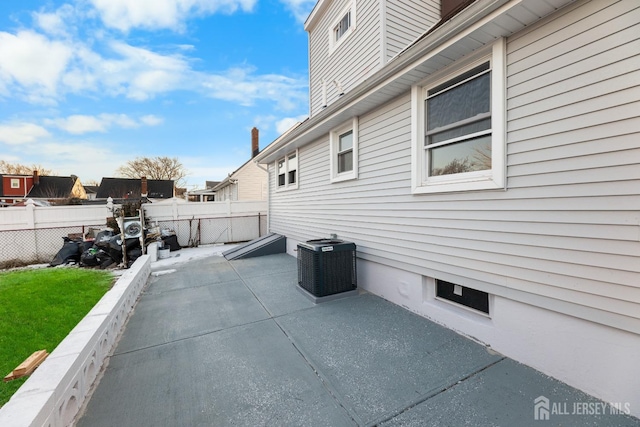 view of property exterior with a patio, fence, and central AC