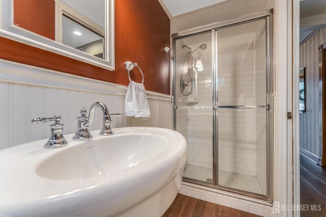 14 Bonnie Brook Ter, Middlesex, NJ 08846 - bathroom with wood finished floors, a shower stall, a sink, wainscoting, and a decorative wall
