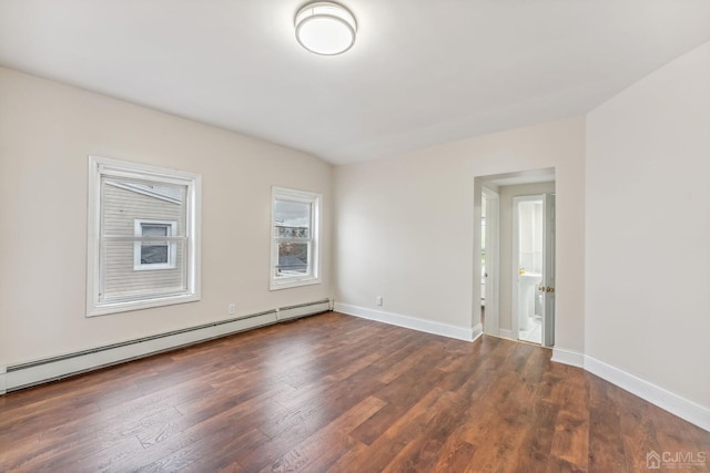 spare room featuring a baseboard radiator, baseboards, and wood finished floors