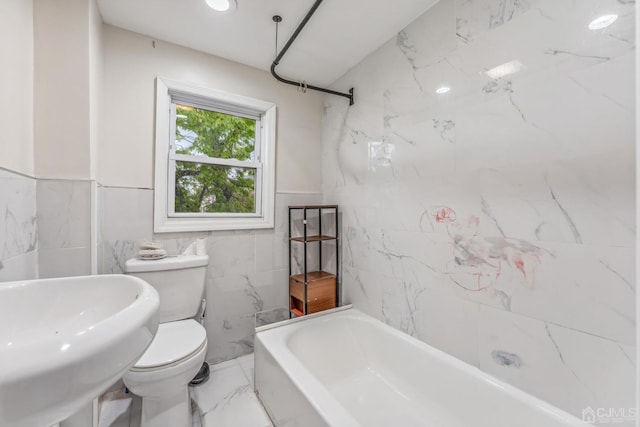 bathroom featuring toilet, a bath, marble finish floor, and a sink