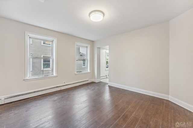 spare room with a baseboard radiator, baseboards, and dark wood finished floors