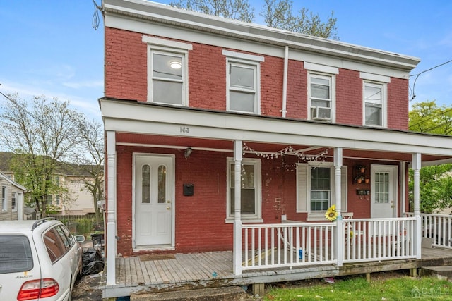 view of front facade featuring brick siding and a porch