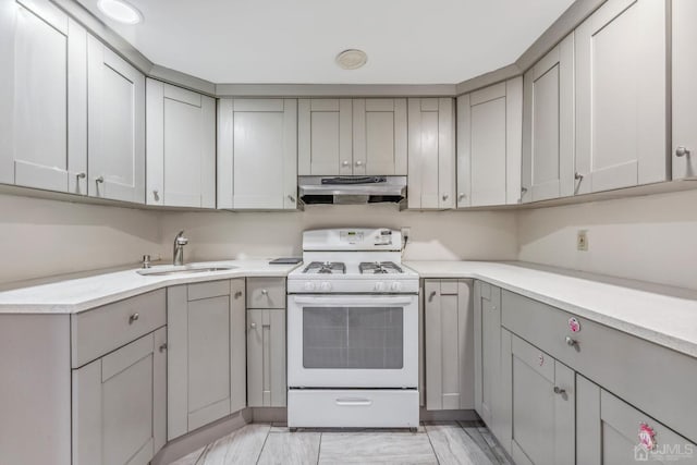 kitchen with range hood, gray cabinets, a sink, light countertops, and white gas range oven