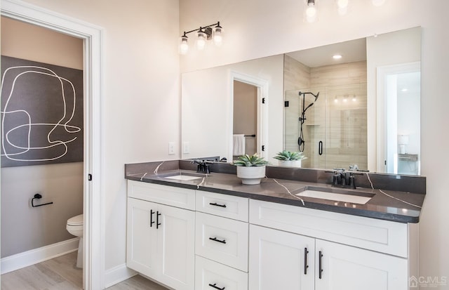 bathroom with hardwood / wood-style flooring, vanity, an enclosed shower, and toilet