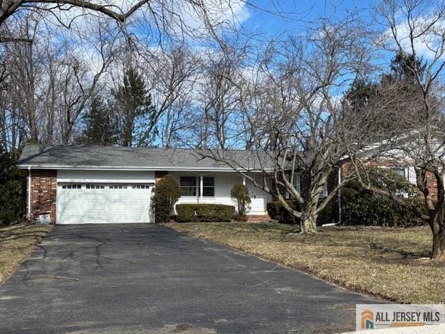 single story home with aphalt driveway, an attached garage, and brick siding