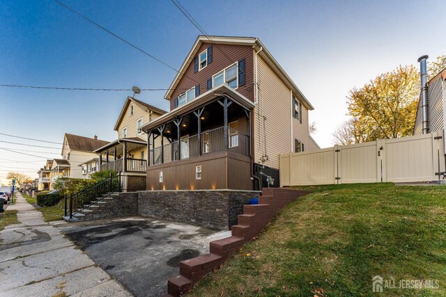 view of side of property with a balcony and a lawn