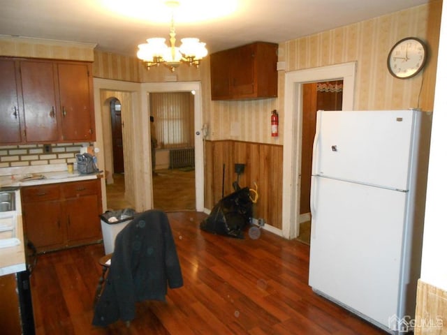 kitchen featuring dark hardwood / wood-style flooring, an inviting chandelier, radiator, and white fridge