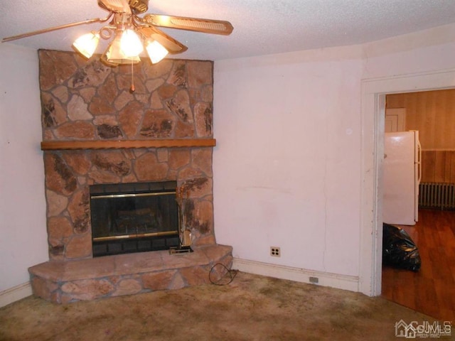 unfurnished living room featuring ceiling fan, a textured ceiling, radiator, and a stone fireplace