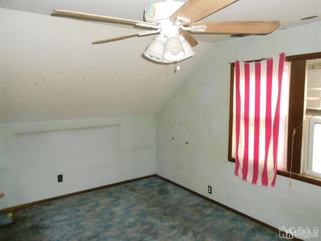 additional living space with dark colored carpet, vaulted ceiling, and ceiling fan