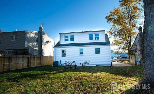 back of property with central AC unit and a lawn