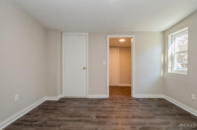 unfurnished bedroom featuring dark wood finished floors, visible vents, and baseboards