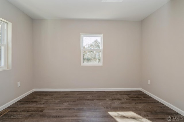 empty room featuring baseboards and dark wood finished floors