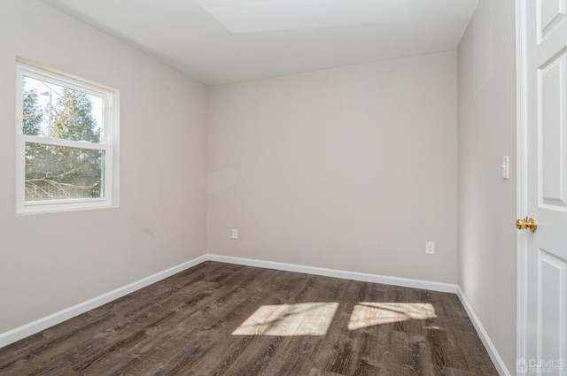 spare room featuring dark wood-type flooring and baseboards