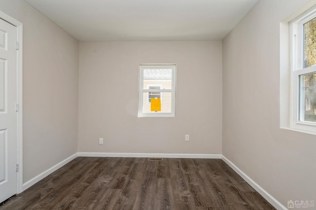 unfurnished room with visible vents, baseboards, and dark wood finished floors