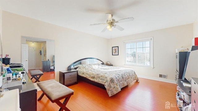 bedroom with a ceiling fan, baseboards, visible vents, and wood finished floors