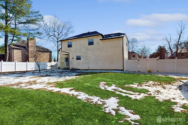 snow covered property with a gate, a fenced backyard, and a yard