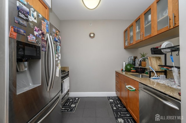 1 Spring St Unit 1206, New Brunswick, NJ 08901 - kitchen featuring stainless steel appliances, brown cabinetry, dark tile patterned floors, glass insert cabinets, and light stone counters