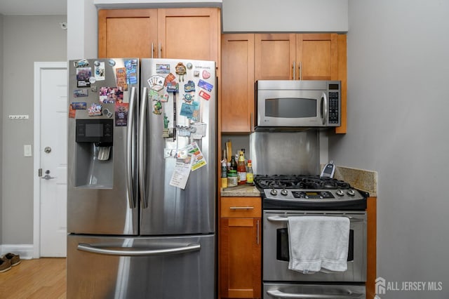 1 Spring St Unit 1206, New Brunswick, NJ 08901 - kitchen with appliances with stainless steel finishes, brown cabinetry, light wood-type flooring, and light stone counters