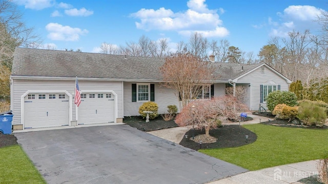 single story home with a shingled roof, a front yard, driveway, and an attached garage