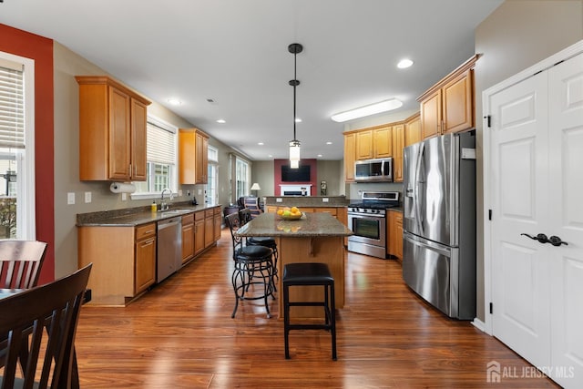 55 Dahlia Ct, Piscataway, NJ 08854 - kitchen with appliances with stainless steel finishes, a kitchen island, dark wood finished floors, a breakfast bar area, and recessed lighting