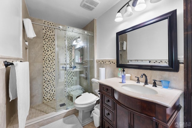 bathroom with walk in shower, vanity, toilet, and tile walls