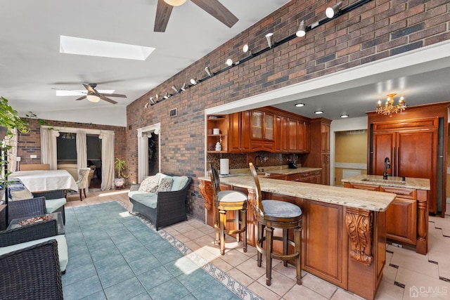 kitchen featuring a kitchen bar, sink, light tile patterned floors, kitchen peninsula, and ceiling fan