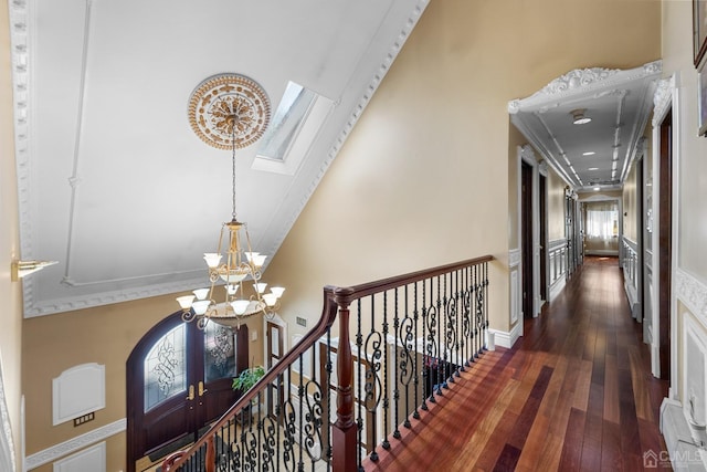 hallway featuring dark wood-type flooring, high vaulted ceiling, and a notable chandelier