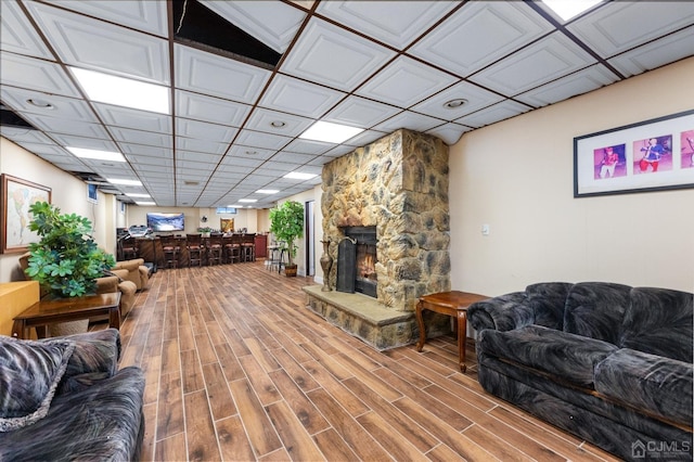 living room with a drop ceiling, hardwood / wood-style floors, and a fireplace