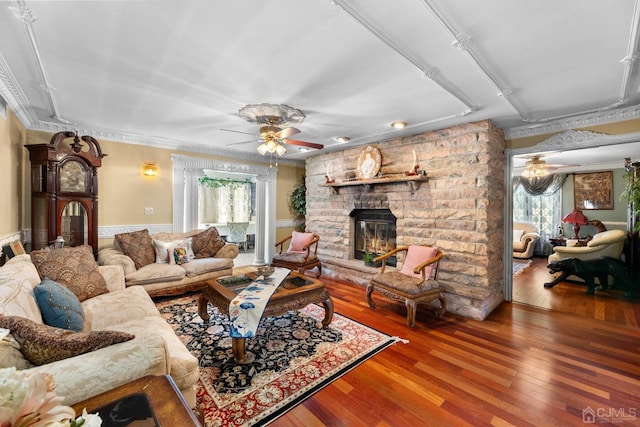 living room featuring hardwood / wood-style flooring, a fireplace, ornamental molding, and ceiling fan