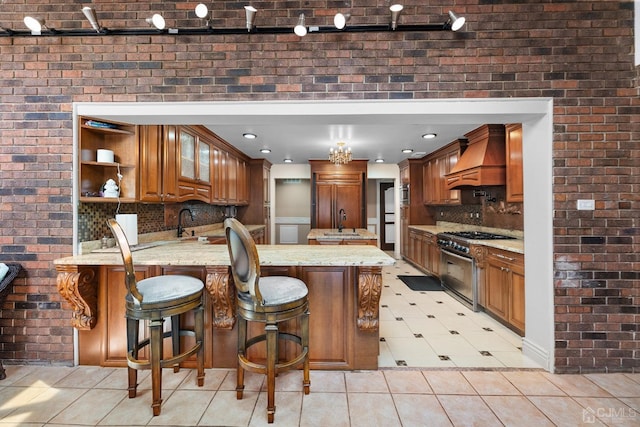 kitchen featuring a breakfast bar, high quality appliances, light stone countertops, custom exhaust hood, and kitchen peninsula