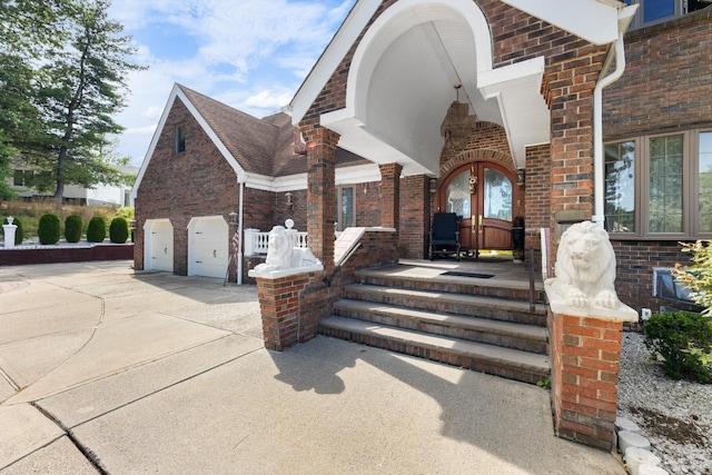 entrance to property featuring brick siding, an attached garage, and concrete driveway