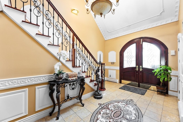 tiled entrance foyer with french doors, lofted ceiling, and a baseboard heating unit