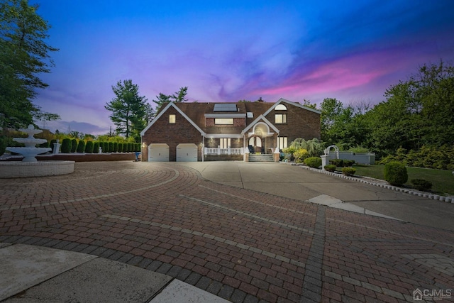 view of front of house with brick siding, fence, roof mounted solar panels, decorative driveway, and a garage