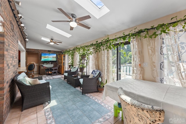 interior space with vaulted ceiling with skylight, a sunroom, ceiling fan, tile patterned flooring, and access to exterior