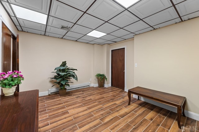 interior space featuring baseboard heating, a paneled ceiling, and hardwood / wood-style floors